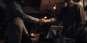 Two people in aprons shake hands, building a brand community for sustainable growth.