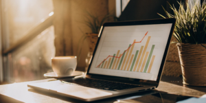 A laptop screen showing how to use AI for Facebook ads with performance analytics and graphs.